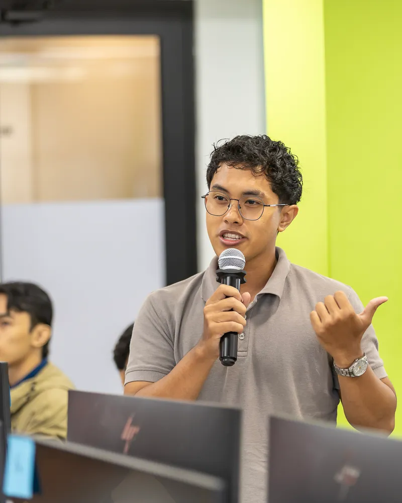 Speaking with a microphone during a session at Gamuda AI Academy